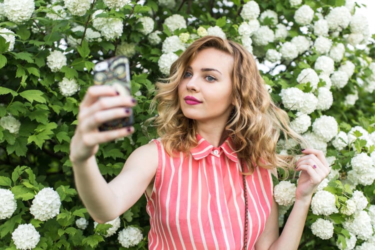 Woman taking selfie with greenery background
